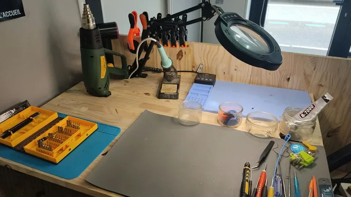 L'établi de soudure de l'atelier : loupe éclairante, fer à souder, station et outils de précision